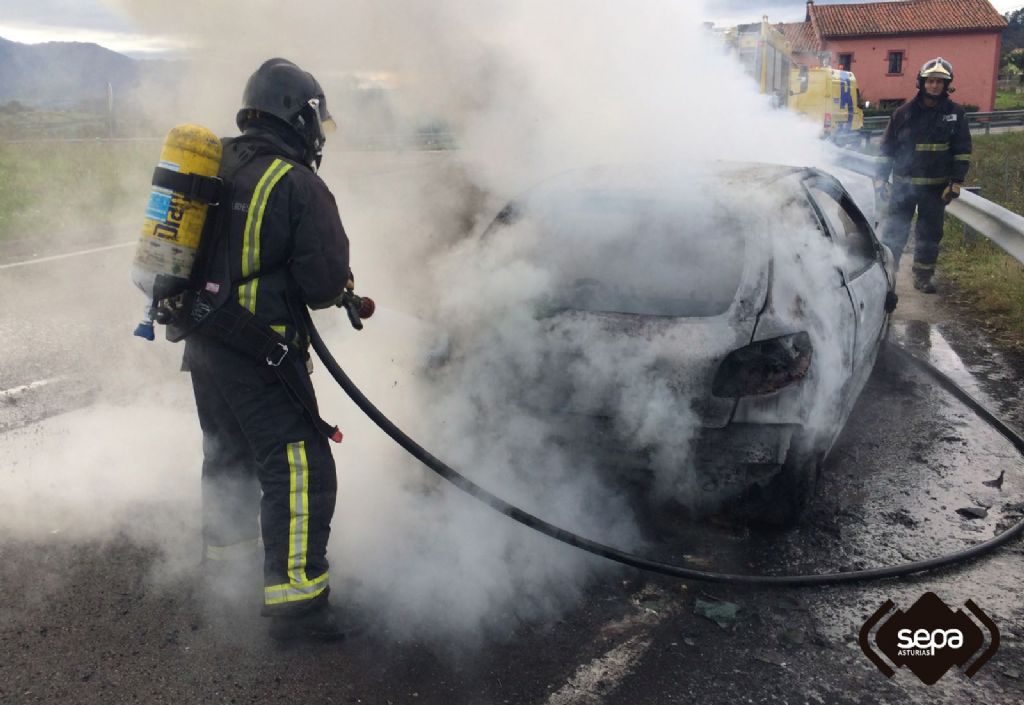 Bomberos trabajando en la extincin del incendio de un coche en Villaviciosa.